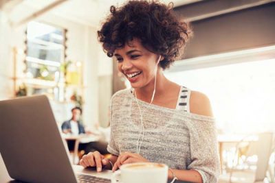 Image of happy woman using laptop while sitting at a cafe.